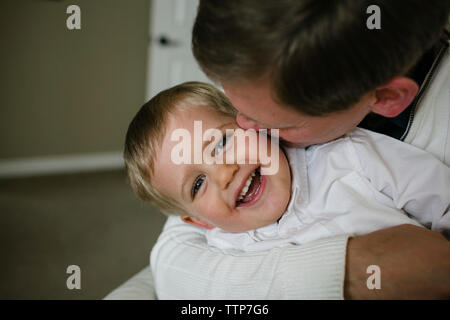 Gerne Vater Sohn küssen, während zu Hause sitzen Stockfoto