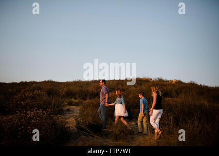 Familie wandern von Pflanzen auf dem Feld gegen den klaren Himmel bei Sonnenuntergang Stockfoto