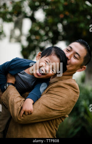 Low Angle View von Vater, Sohn glücklich beim Stehen gegen Bäume im Balboa Park Stockfoto