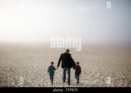 Vater und zwei Söhne zu Fuß am Strand an einem nebligen Nachmittag in San Diego Stockfoto