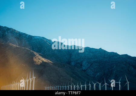 Windenergieanlagen durch Rocky Mountain gegen den klaren Himmel Stockfoto
