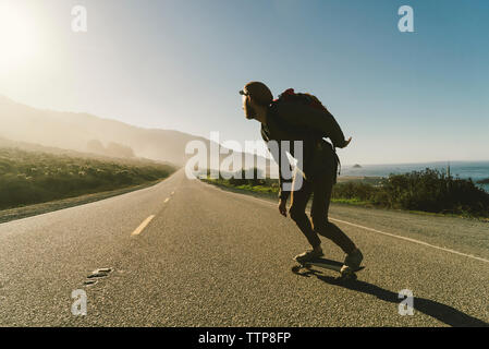 Volle Länge des Menschen skateboarding auf Landstraße Stockfoto