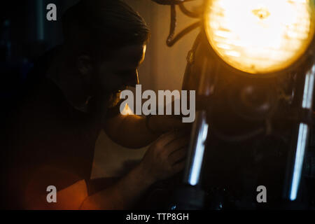 Close-up des Menschen prüfen beleuchtete Motorrad in einer Garage. Stockfoto