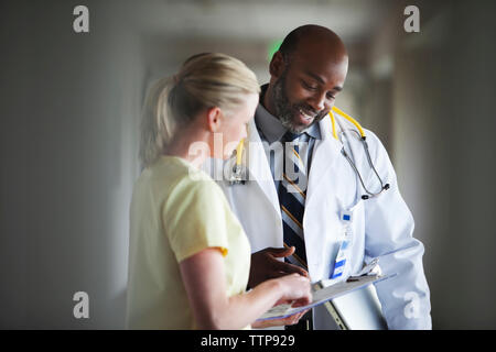 Männlicher Arzt Kontrolle Papiere mit Krankenschwester im Krankenhaus Stockfoto