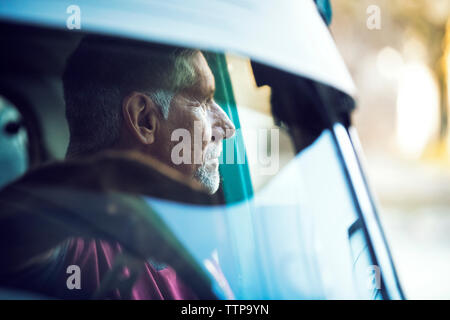 Nachdenklicher Mann sitzt im Auto durch die Windschutzscheibe sichtbar Stockfoto