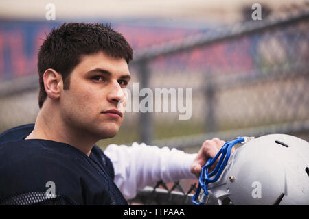 American football player weg schauen beim Stehen durch Zaun im Stadion Stockfoto