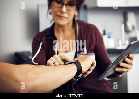 Ärztin überprüfen Zeit auf des Patienten Armbanduhr in Klinik Stockfoto