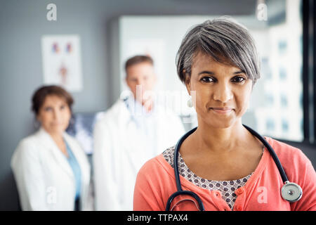 Portrait von zuversichtlich, Ärztin in der Klinik mit Kollegen im Hintergrund stehend Stockfoto