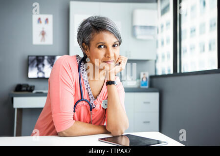 Portrait von zuversichtlich Ärztin lehnte sich auf dem Schreibtisch, in der Klinik Stockfoto