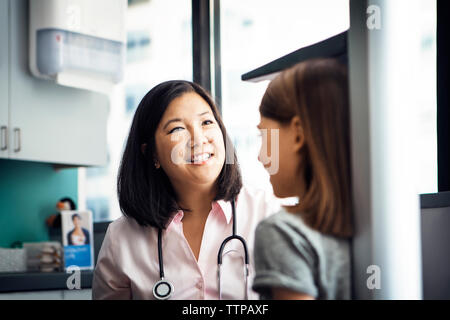 Lächelnd Höhe der Frauen Arzt messen Mädchen in der Klinik Stockfoto