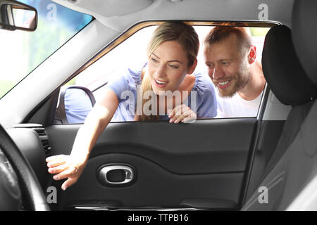 Junges Paar im neuen Auto suchen Stockfoto