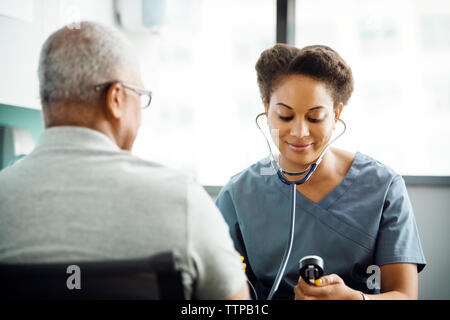 Ärztin Kontrolle Blutdruck der männlichen Patienten in der Klinik Stockfoto