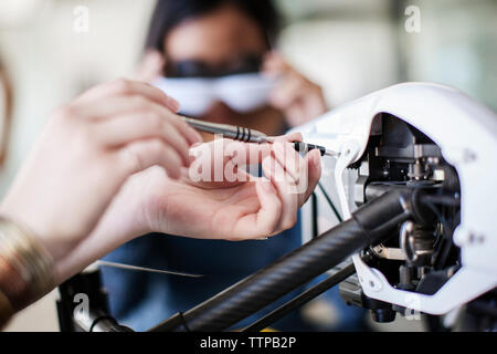 Zugeschnittenes Bild der weiblichen Schüler arbeiten an Drone mit Freund im Hintergrund Stockfoto