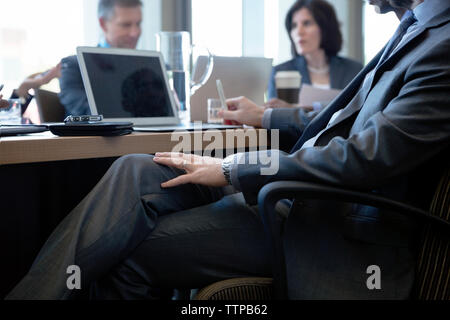 Geschäftsmann, der während der Besprechung im Büro am Schreibtisch sitzt Stockfoto