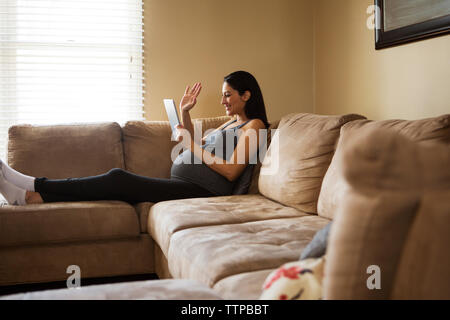 Schwangere Frau gestikuliert während der Verwendung von Tablet Computer zu Hause. Stockfoto