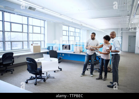 Geschäftsleute diskutieren während sie im Büro stehen Stockfoto