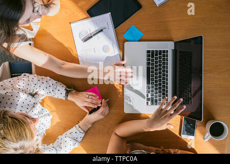 Hohe Betrachtungswinkel von weiblichen Kollegen, die Analyse von Daten, die auf Notebook Computer Board Zimmer Stockfoto