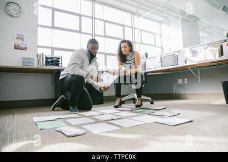 Low Angle View der Kollegen, die die Dokumente auf dem Boden im Büro Stockfoto