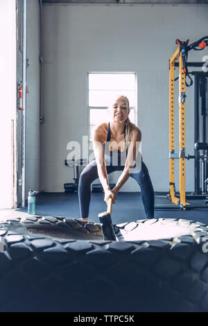 Bestimmt Frau schlagen Reifen mit vorschlaghammer während des Trainings in der Turnhalle Stockfoto