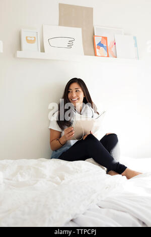Happy woman holding Tagebuch während auf dem Bett zu Hause sitzen Stockfoto