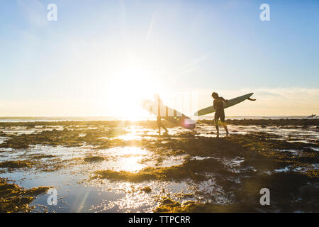 Paar Durchführung Surfboards beim Gehen auf San Onofre Strand während der Ferien Stockfoto