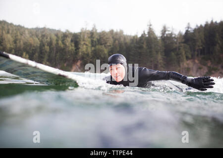 Portrait von Frau liegend auf Surfbrett im Meer Stockfoto