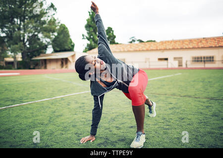 Bestimmt weiblichen Athleten zu tun stretching Übung auf Feld Stockfoto