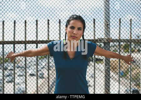 Portrait von zuversichtlich Athlet gegen chainlink fence Stockfoto