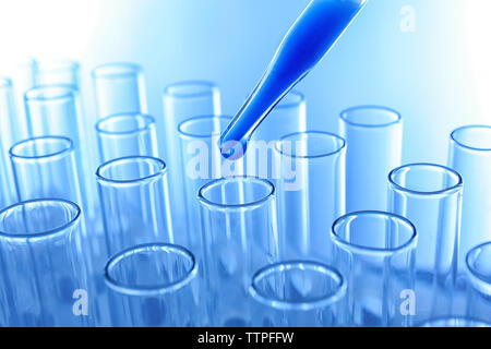 Nahaufnahme von einer Pipette Fallenlassen einer blauen Probe in ein Reagenzglas Stockfoto