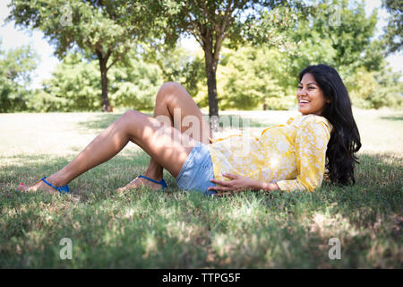 Glücklich schwanger liegende Frau auf Gras im Park Stockfoto