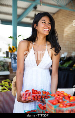 Gerne Frau mit Tomate Körbe beim Einkaufen im Supermarkt Stockfoto