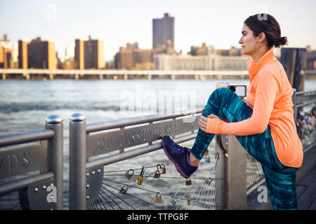 Seitenansicht des weiblichen Athleten stretching Beine auf der Promenade in der Stadt Stockfoto