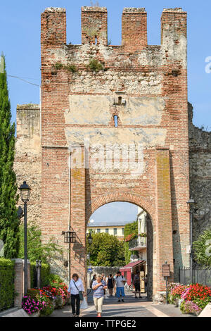 LAZISE, Gardasee, Italien - September 2018: Menschen zu Fuß von der Stadt vorbei an der alten Stadtmauer in Lazise am Gardasee. Stockfoto