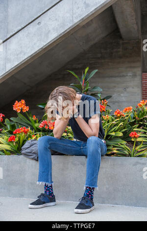 Männliche Kursteilnehmer sitzen und das Gesicht in die Hände Stockfoto