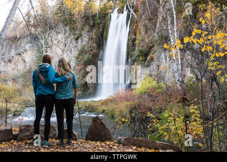 Volle Länge von Mutter und Tochter auf Wasserfall beim Stehen in Wald bei Badlands National Park Stockfoto