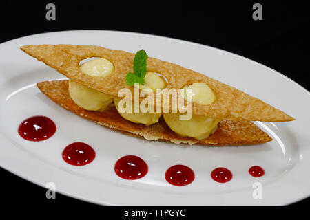 Vanilleeis cremefarben mit Himbeer-Coulies und knusprigem puf-Gebäck Stockfoto