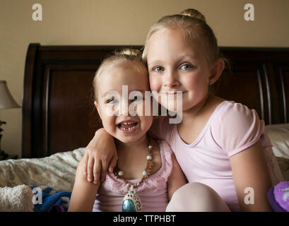 Portrait von Happy Schwestern im Ballett Kostüme auf dem Bett zu Hause sitzen Stockfoto