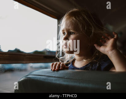 In der Nähe von Mädchen auf der Suche durch das Fenster beim Stehen in Bus Stockfoto