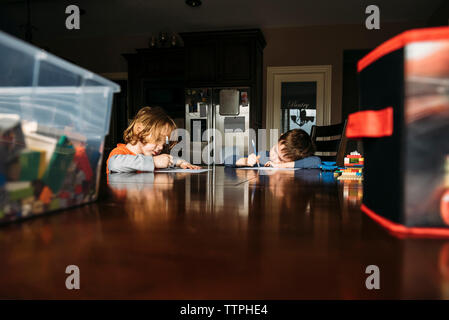 Geschwister studieren beim Sitzen am Küchentisch Stockfoto