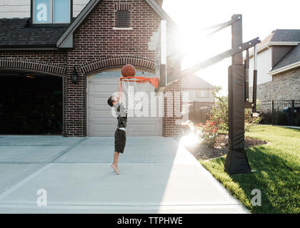 Seitenansicht des Jungen Basketball spielen im Hof Stockfoto