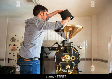 Man gießt Kaffee Bohnen in Kaffeemühle im Cafe Stockfoto