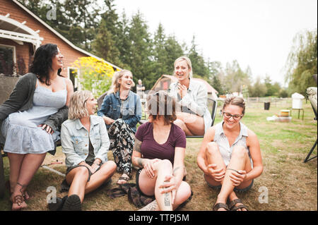 Gerne weibliche Freunde sprechen während der Sitzung gegen den Himmel in Hof Stockfoto