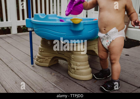 Baby spielt mit wasser Spielzeug in der Windel Stockfoto