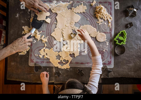 Blick von oben auf die Enkelin, die Großmutter bei der Herstellung von weihnachtskeksen auf dem Tisch zu Hause hilft Stockfoto