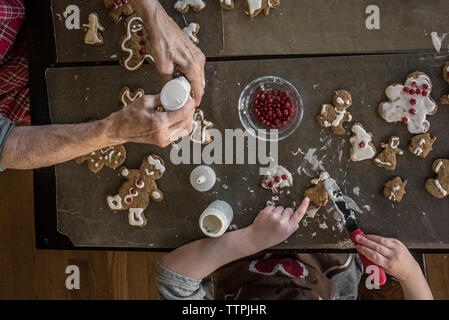 7/8 Hand der Großmutter und Enkelin, Lebkuchen Männer zu Hause Stockfoto