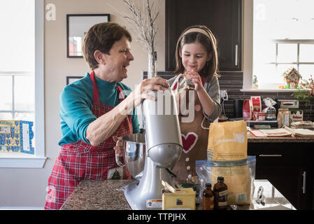 Gerne Großmutter und Enkelin, die Cookie Teig mit elektrischen Mixer in der Küche zu Hause. Stockfoto