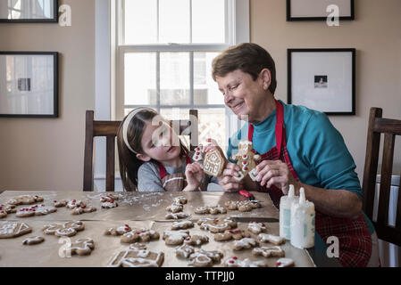 Süße Enkelin, Gingerbread cookies zu Großmutter zu Hause Stockfoto