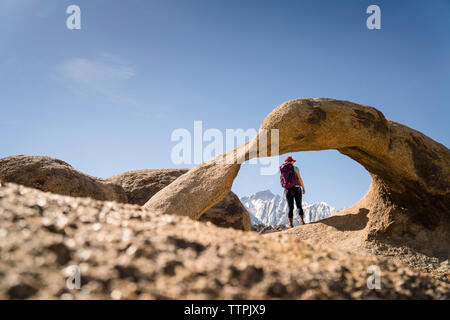 Ansicht der Rückseite Frau mit Rucksack steht die Felsformation an einem sonnigen Tag Stockfoto