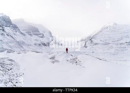 Mitte der Abstand der Wanderer auf schneebedeckten Landschaft während nebligen Wetter Stockfoto