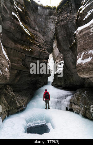 Ansicht der Rückseite des Wanderer mit Rucksack auf gefrorenen Stream inmitten von Bergen Stockfoto